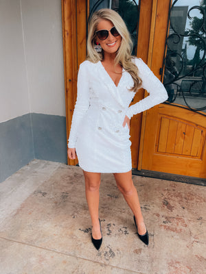 Dress features a white full sequin base, long sleeves, deep V-neck line, back zipper closure, faux double button front detailing, mini length and runs true to size! 
