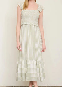 Woman wearing a light green dress with ruffled sleeves against a plain background