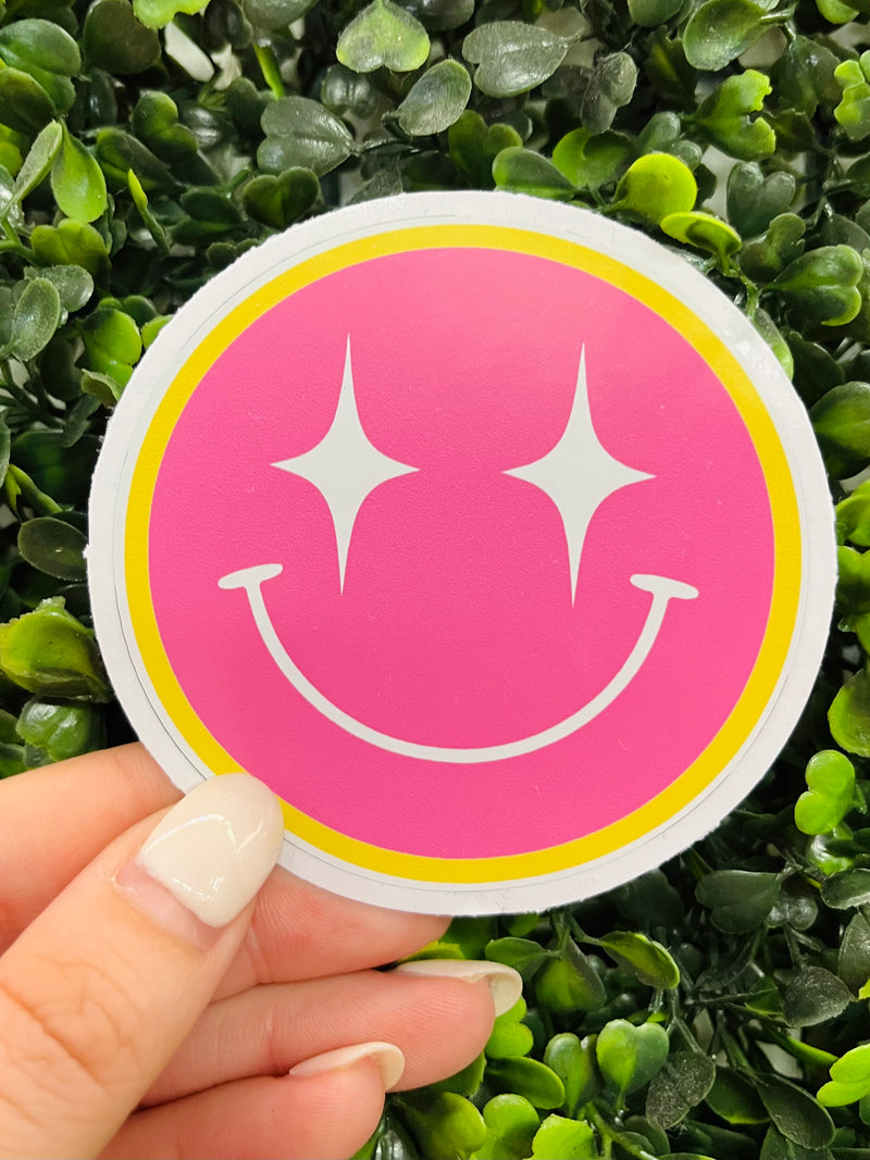 Let your style shine with this Star Smile Face Sticker! Show off the cute pink smile, starry eyes and radiant gold trim – all in one playful sticker. Make it the star of your look and give everyone something to smile about!