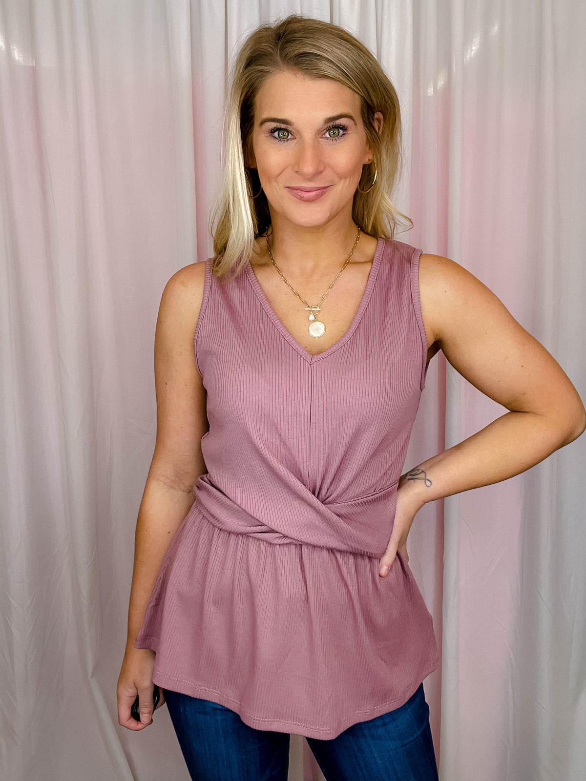 This top is crafted from ribbed mauve fabric, featuring an eye-catching front twist knot and a flattering V-neck. With its sleeveless design, you can enjoy the perfect style balance between comfort and fashion.