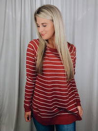 Top features a solid base color, ivory striped detailing, boat neck line, long sleeves, U-shaped hemline, and runs true to size! -rust