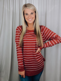 Top features a solid base color, ivory striped detailing, boat neck line, long sleeves, U-shaped hemline, and runs true to size! -rust