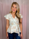 Our Flirty Darling Top showcases a mint base adorned with a beautiful floral print, featuring short sleeves and a V-neck line. The waist is cinched for a flattering fit, and tie detail adds a romantic touch. Make a statement with this elegant and feminine piece.