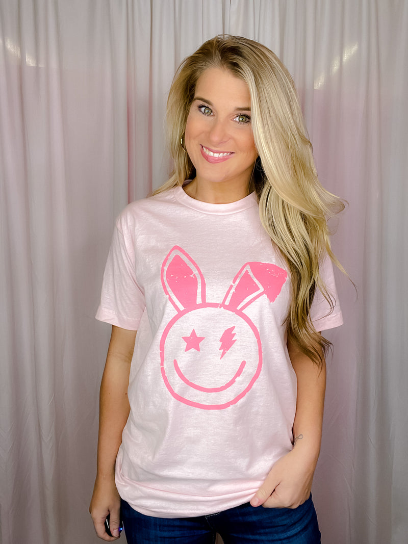 This Smile Face Bunny Tee is the perfect addition to your wardrobe. With its smile face, lighting bolt eyes, bunny ears, short sleeves, and round neck line, this unisex fit shirt will add a cheerful touch to your summer look. Best of all, it's comfortable and cute for the upcoming holiday! -white