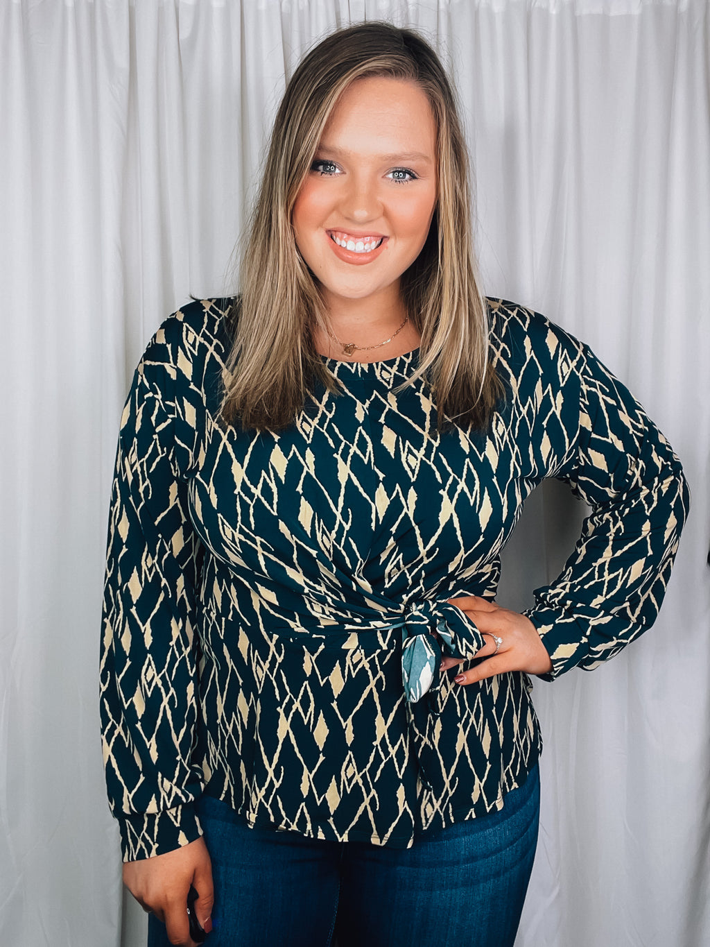 Top features a hunter green base, cream abstract print, long sleeves, V-neck line, tie front detail and runs true to size! 