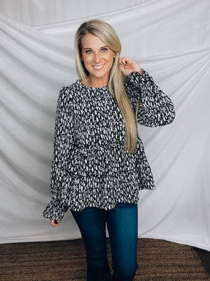 Top features a solid base color, paint stroke design, long sleeves, round neck, light weight material, cinched ruffle sleeves and runs true to size!   100% Polyester -BLACK