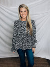 Top features a solid base color, paint stroke design, long sleeves, round neck, light weight material, cinched ruffle sleeves and runs true to size!   100% Polyester -BLACK