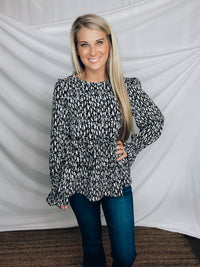 Top features a solid base color, paint stroke design, long sleeves, round neck, light weight material, cinched ruffle sleeves and runs true to size!   100% Polyester -BLACK