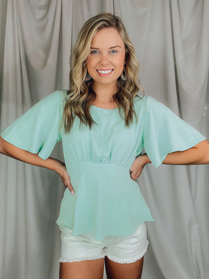 Top features a solid base color, boat neck, short sleeves, ruched front, textured material and runs true to size!-MINT