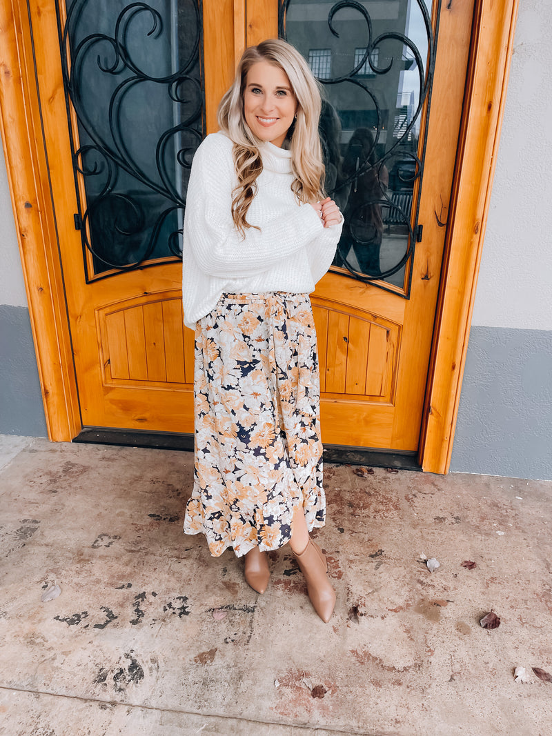 Skirt features a navy base, white & mustard floral print, ruffle skirt bottom, elastic waist band, tie belt detail and runs true to size! 