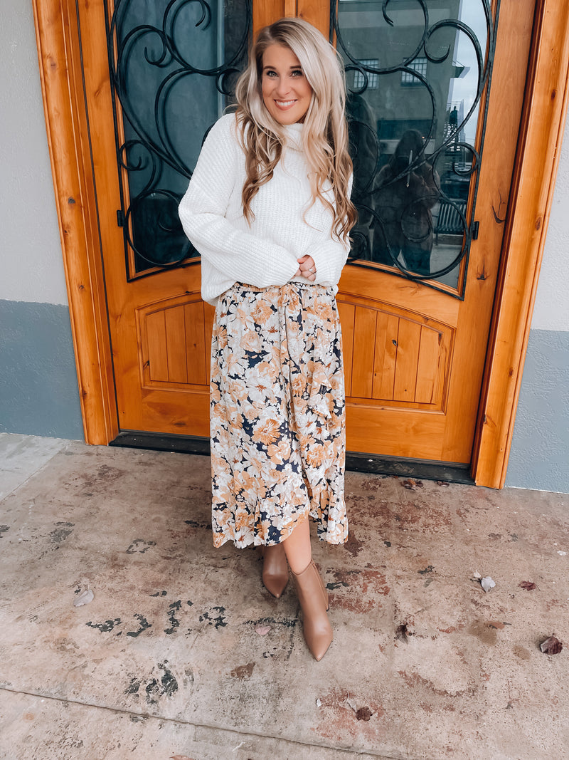 Skirt features a navy base, white & mustard floral print, ruffle skirt bottom, elastic waist band, tie belt detail and runs true to size! 