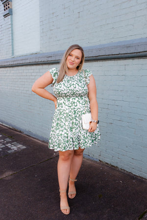 Dress features a green base, white floral print, smocked chest detail, crew neck line, ruffle hem line, fully lined underneath and runs true to size!