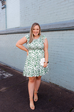 Dress features a green base, white floral print, smocked chest detail, crew neck line, ruffle hem line, fully lined underneath and runs true to size!