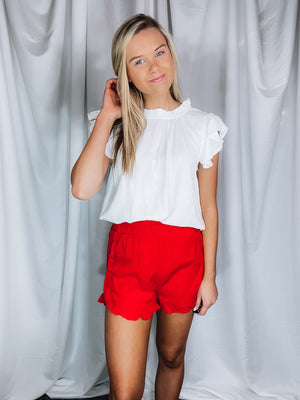 Bottoms feature a solid base color, elastic waistband, ruffle detailing around the pockets and bottom of the shorts, functional pockets, under lining and runs true to size!-tomato