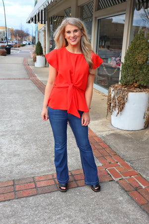 Top features a solid base color, front tie detail, short flutter sleeves, round neck line, elastic waist, and runs true to size! -red