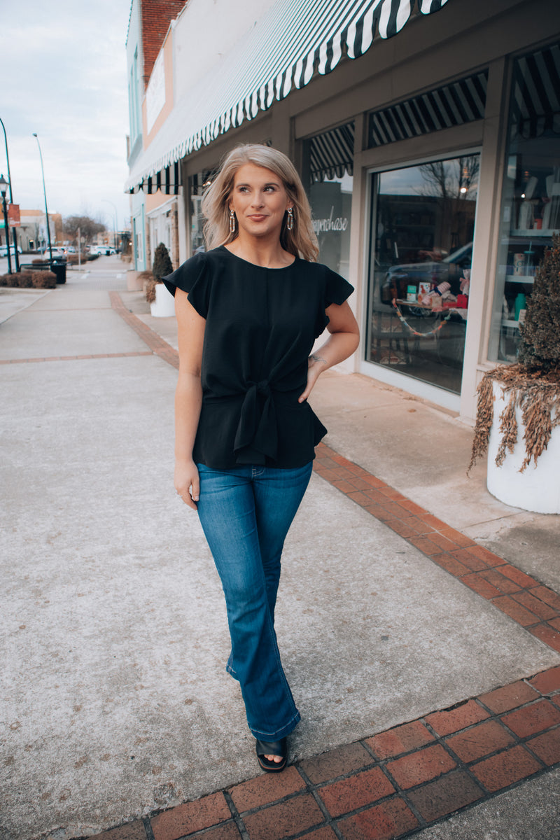 Top features a solid base color, front tie detail, short flutter sleeves, round neck line, elastic waist, and runs true to size! -black