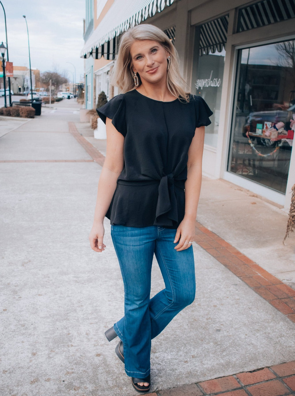 Top features a solid base color, front tie detail, short flutter sleeves, round neck line, elastic waist, and runs true to size! -black