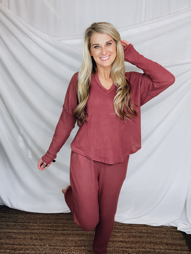 This lounge set features a solid base color, soft material, top with a V-neck line and long sleeves, jogger high waisted pants, surplus pockets with a drawstring and runs true to size!-MARSALA