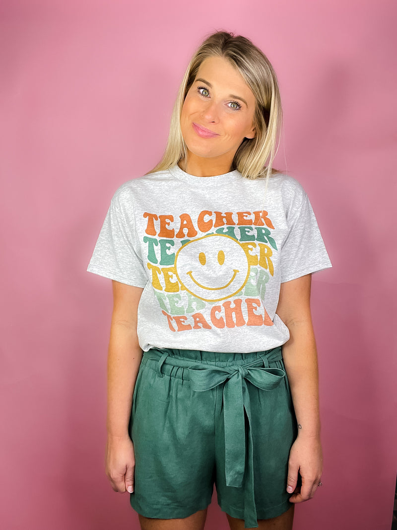 Nab this Teacher Smile Face Graphic Tee for a real 'A+' look! Show your appreciation for the education system with this quirky, unisex tee complete with a smiley face, short sleeves, and a round neck line. Let your fashion choices do the teachin'!