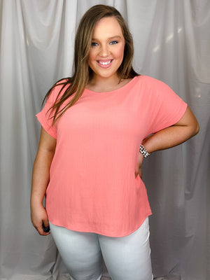 Top features a solid base color, soft lightweight textured material, cuffed short sleeves, round neck line and runs true to size!-coral