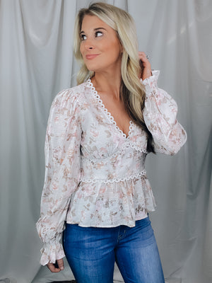 Top features an ivory base, light floral colored print, V-neck line, baby doll fit, eyelet trim, long sleeve, elastic wrist, light weight material and runs true to size!  Materials:  74% Rayon / 26% Nylon
