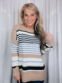 Sweater features a taupe and ivory base, black & blue stripes, long sleeves, round neck line and runs true to size! SUPER SOFT + COZY!