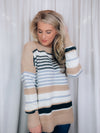 Sweater features a taupe and ivory base, black & blue stripes, long sleeves, round neck line and runs true to size! SUPER SOFT + COZY!