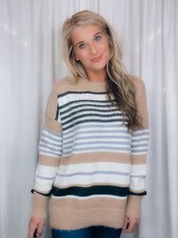 Sweater features a taupe and ivory base, black & blue stripes, long sleeves, round neck line and runs true to size! SUPER SOFT + COZY!