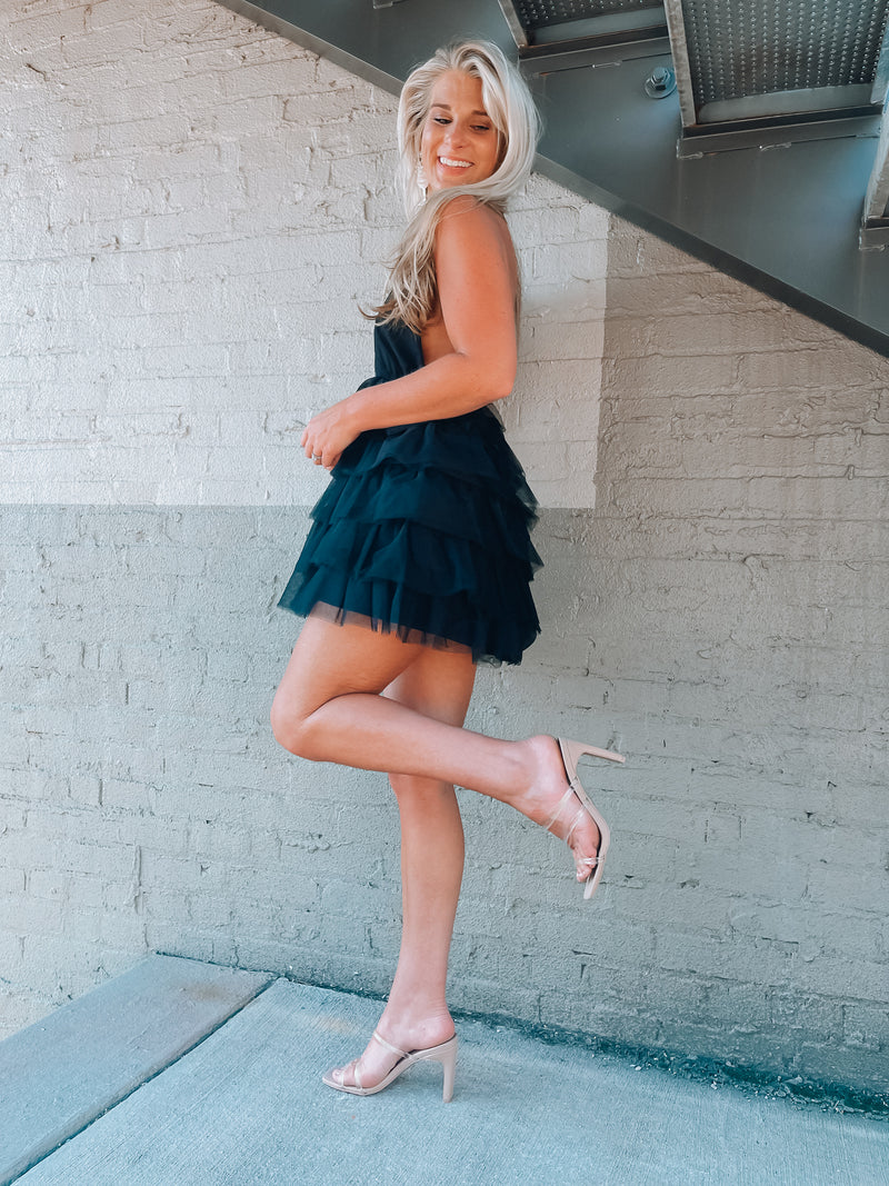 Tulle dress features a base color with a deep V cut-out, adjustable tie detail around the neck, and elastic waistband with an open back. Runs true to size!-black