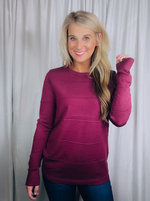 Top features a solid base color, long sleeves, horizontal line detailing, crew neck line and runs true to size!-magenta