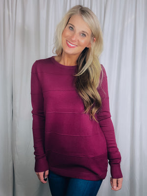 Top features a solid base color, long sleeves, horizontal line detailing, crew neck line and runs true to size!-magenta