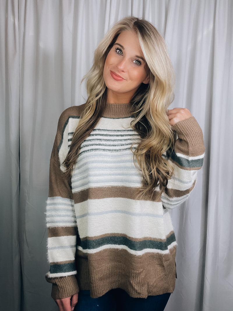 Sweater features a taupe base, multi colored striped print, long sleeves, round neck line and runs true to size! 