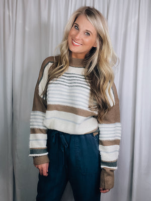 Sweater features a taupe base, multi colored striped print, long sleeves, round neck line and runs true to size! 