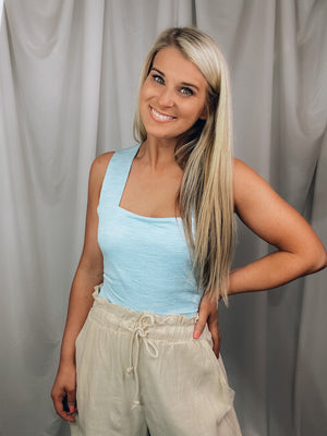 Bodysuit features a heathered light blue color, square neck line, sleeveless detail, cross-open back detail, snap bottom closure, fitted fit and runs true to size! 