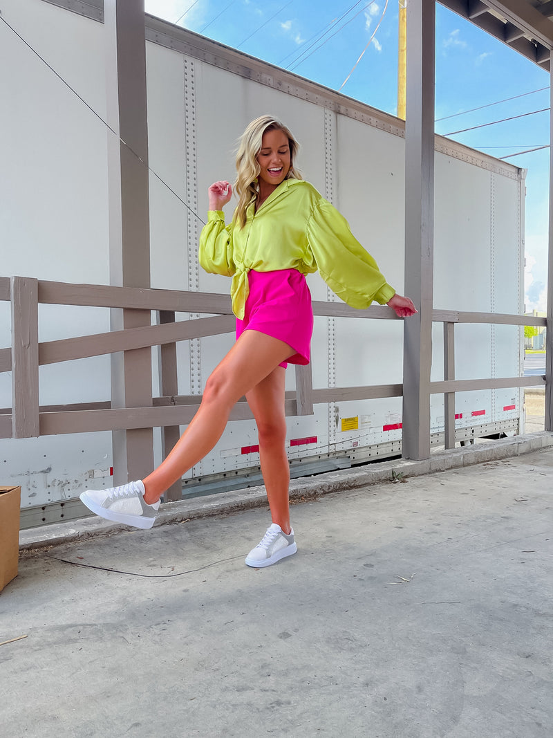 Oversized lime blouse features a button up look with a front tie, collared V-neck, buttoned sleeves, and back elastic waistband. Runs true to size!