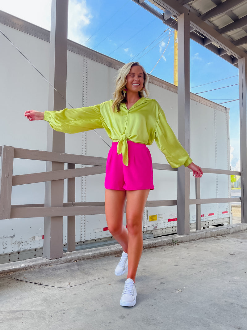 Oversized lime blouse features a button up look with a front tie, collared V-neck, buttoned sleeves, and back elastic waistband. Runs true to size!