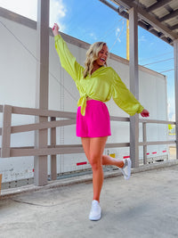 Oversized lime blouse features a button up look with a front tie, collared V-neck, buttoned sleeves, and back elastic waistband. Runs true to size!