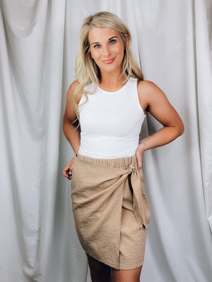 Skirt features solid base color, overlap detail, front tie detail, mini length and runs true to size!-taupe