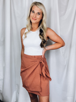 Skirt features solid base color, overlap detail, front tie detail, mini length and runs true to size!-rose