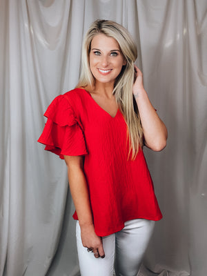 Top features a solid base color, textured look, ruffle sleeves, round neck line, lightweight material and runs true to size!-tomato