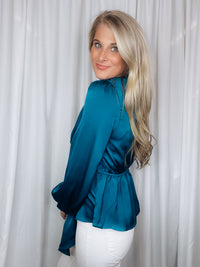 Top features a solid base color, silky material, peplum fit, long sleeves, V-neck line, front draped detail and runs true to size! -teal