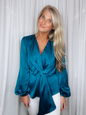 Top features a solid base color, silky material, peplum fit, long sleeves, V-neck line, front draped detail and runs true to size! -teal