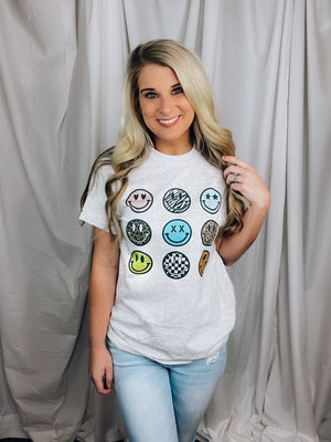Graphic tee features a solid grey base, round neck line, short sleeves, unisex fit, 9 different small smile faces, legging length approval and runs true to size! 