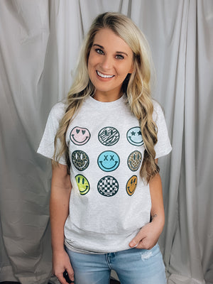 Graphic tee features a solid grey base, round neck line, short sleeves, unisex fit, 9 different small smile faces, legging length approval and runs true to size! 