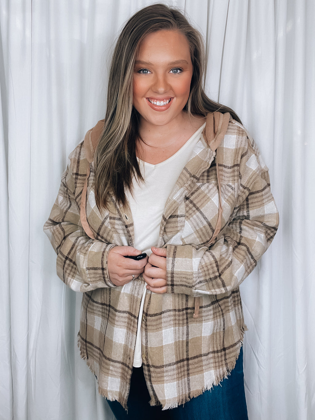 Shacket features a taupe color plaid print, long sleeves, functional button closure, hood detail, frayed hem detail and runs true to size! 