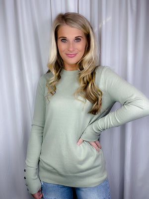 Top features a solid base color, crew neck line, long sleeves, button cuff detailing, soft material and runs true to size! -sage
