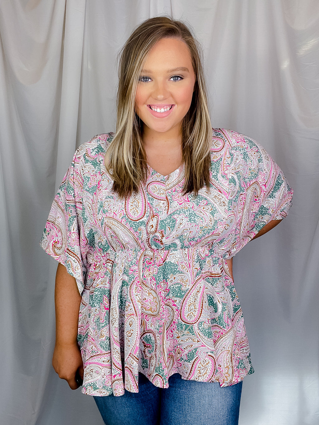 Top features a paisley printed detail, elastic waist band, short dolman sleeves, V-neck line and runs true to size! 