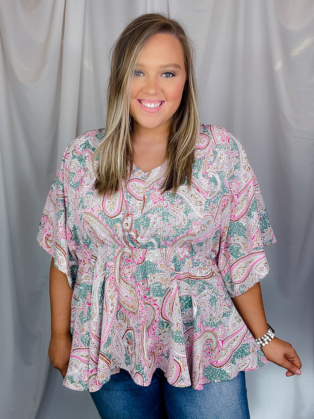 Top features a paisley printed detail, elastic waist band, short dolman sleeves, V-neck line and runs true to size! 
