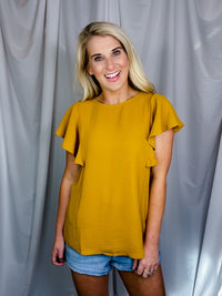 Top features a solid base color, stretchy material, short ruffle sleeves, round neck line and runs true to size!-mustard