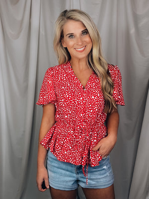 Top features a solid base color, white printed detail, short sleeves, V-neck line, synched waist, adjustable synched waist and runs true to size! 